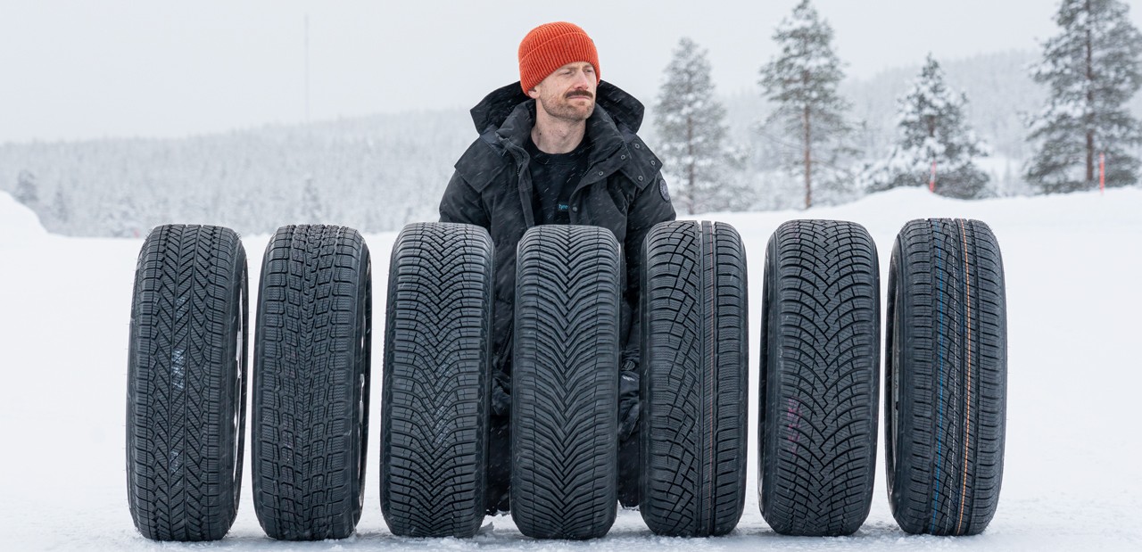 Jonathan Benson on snow behind a row of all-weather tyres at a Tyre Reviews test